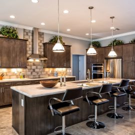 Lakeside Rebuild – In the kitchen we installed dark grey hand painted cabinetry and white granite countertops with a leather finish.